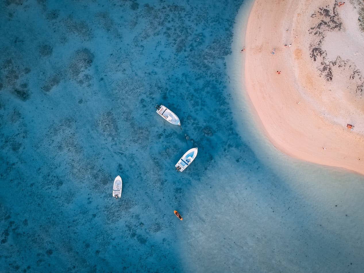 Drei Sportboote vor Anker in türkisblauem Wasser, aus der Luft fotografiert